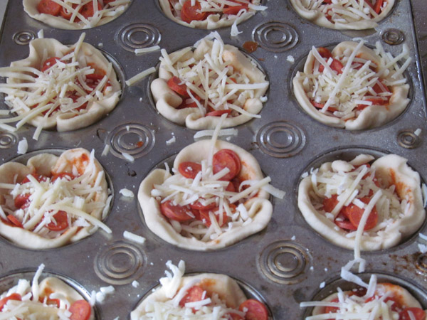 Add toppings and cheese to pizza muffins