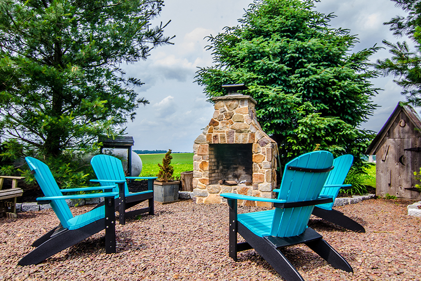patio with blue chairs and a stone fireplace